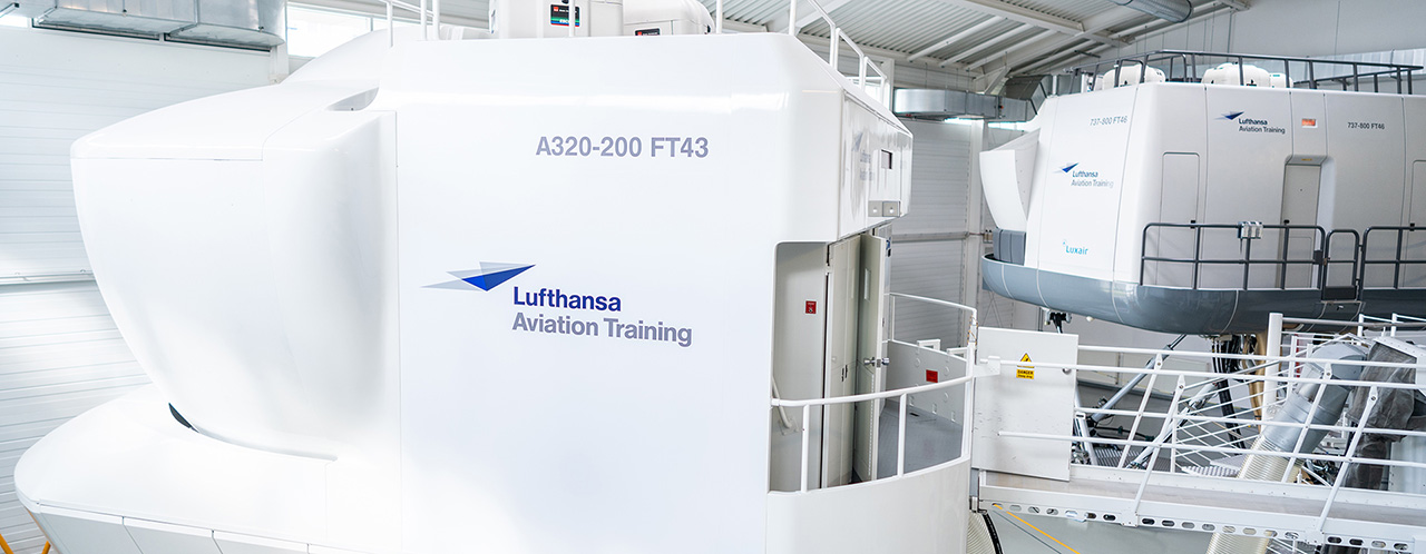 Two flight simulators from Lufthansa Aviation Training are located in a hangar.