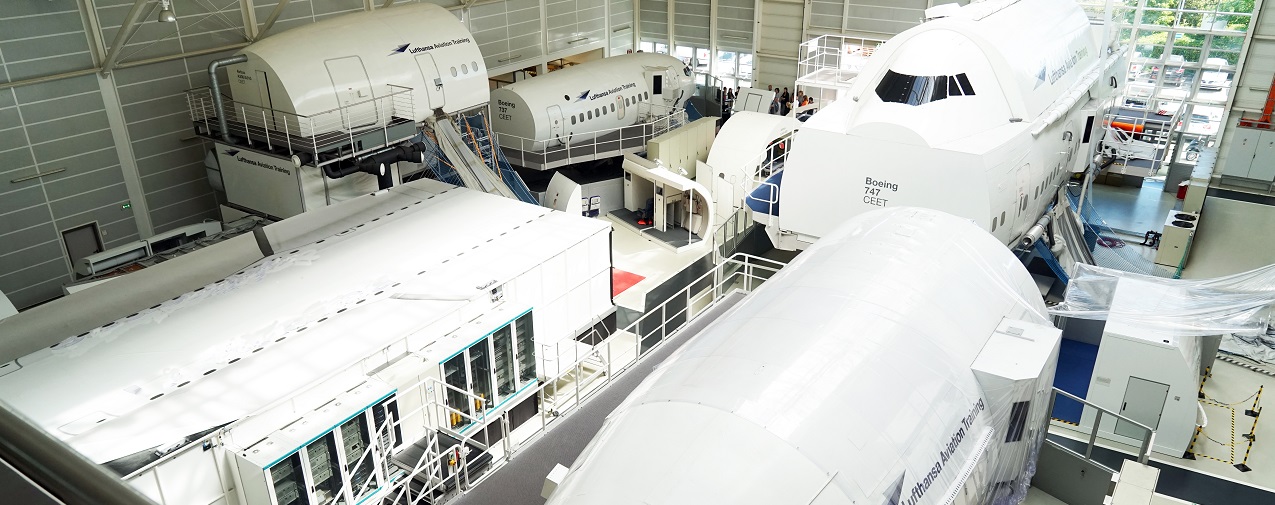 In einer Halle stehen mehrere Cabin Emergency Evacuation Trainer (CEET) von Lufthansa Aviation Training