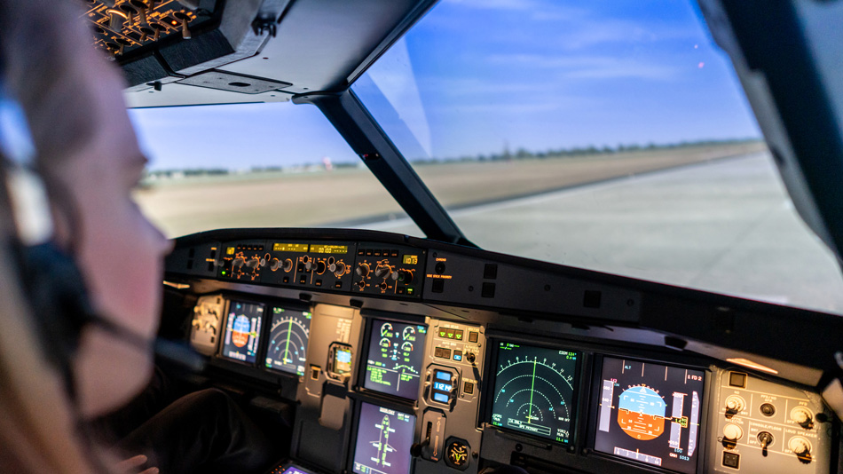 Eine Pilotin sitzt in einem Cockpit-Simulator und schaut auf eine Startbahn