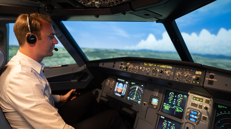 Ein Pilot sitzt in einem Cockpit-Simulator und schaut auf die Instrumente