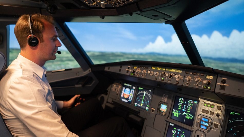 A pilot sits in a cockpit simulator and looks at the instruments