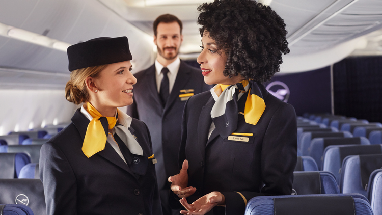 Two female and one male flight attendant on board an empty Lufthansa aircraft