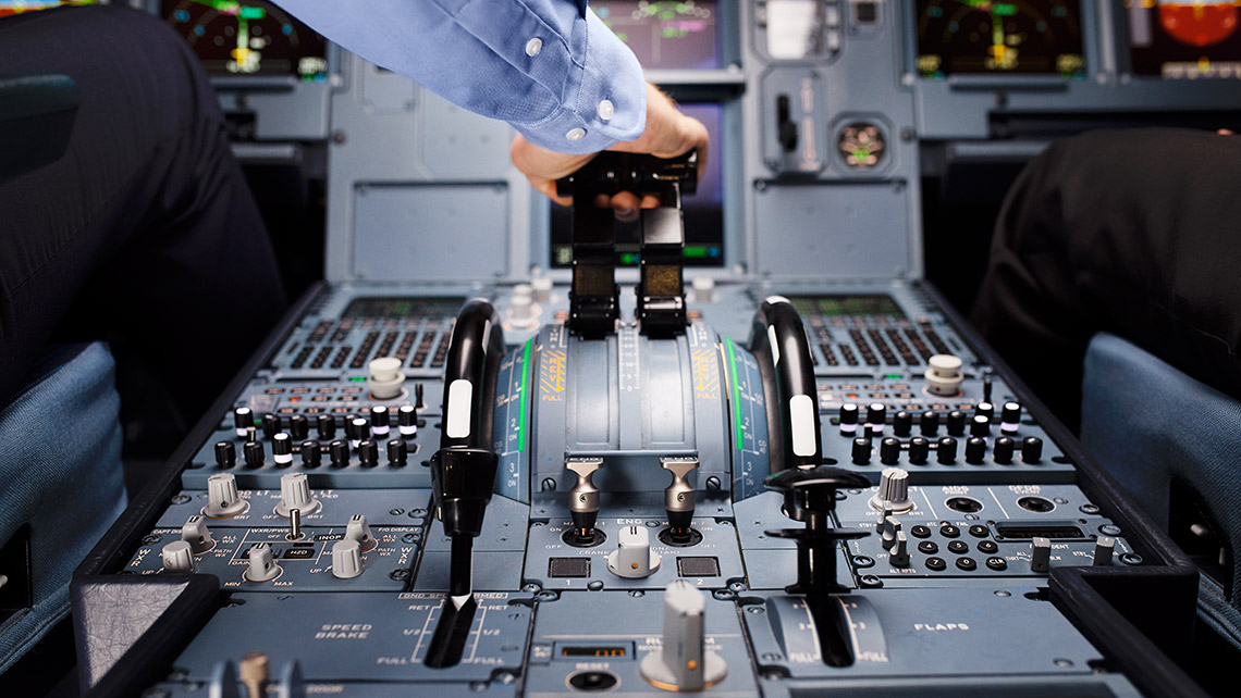 Ein Pilot bedient die Schubhhebel in einem Flugzeugcockpit