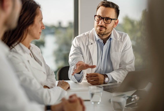 Mehrere Ärzt:innen sitzen an einem Tisch und besprechen sich.