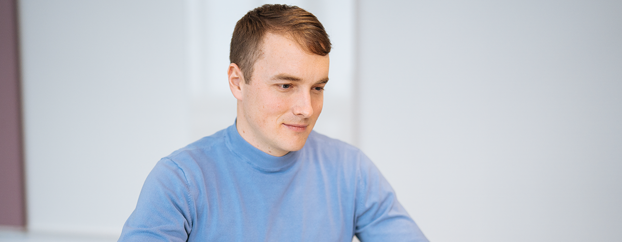 Eine Person unterhält sich lächelnd mit einer anderen Person, von der man nur den Hinterkopf sieht.