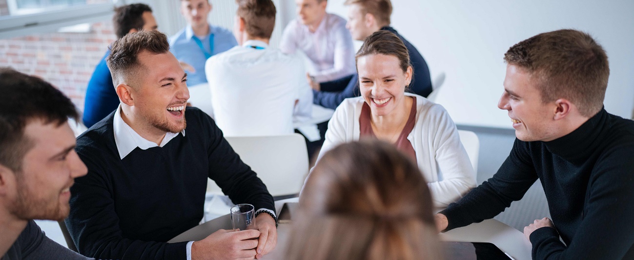 Mehrere Personen sitzen an einem Tisch, unterhalten sich und lachen.