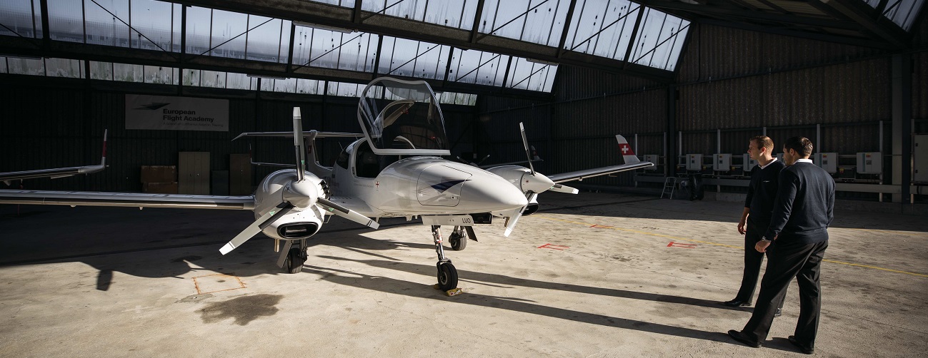 Zwei Flugschüler:innen betrachten ein Schulungsflugzeug in einem Hangar an einem Standort der European Flight Academy.