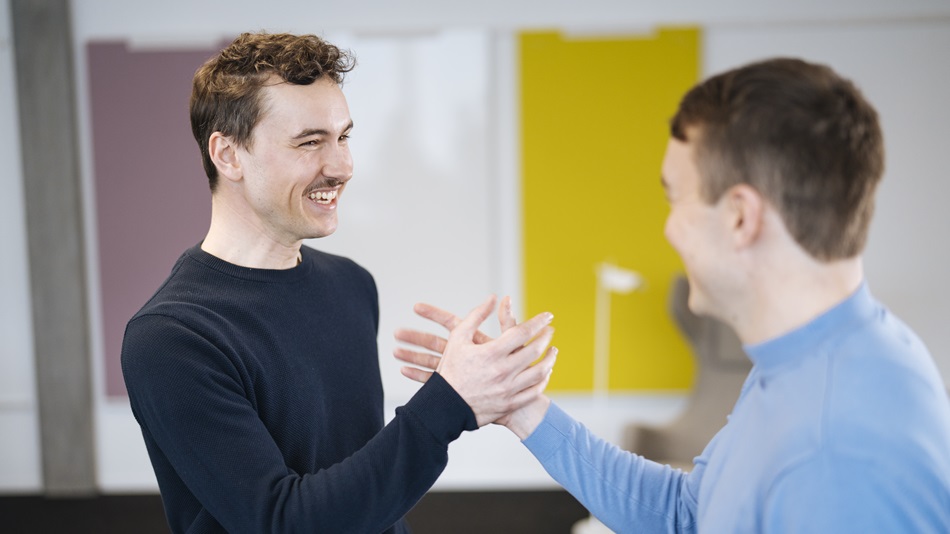 Eine Person sitzt an einem Schreibtisch und schreibt an einem Laptop.