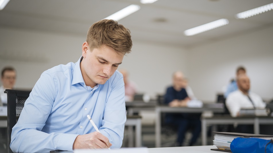 Eine Person sitzt an einem Tisch und schreibt auf einem Laptop an der Bewerbung für eine Pilotenausbildng