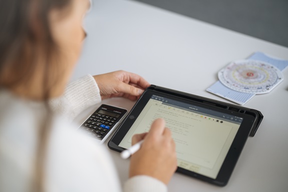 Eine Person sitzt mit einem Taschenrechner über Formularen