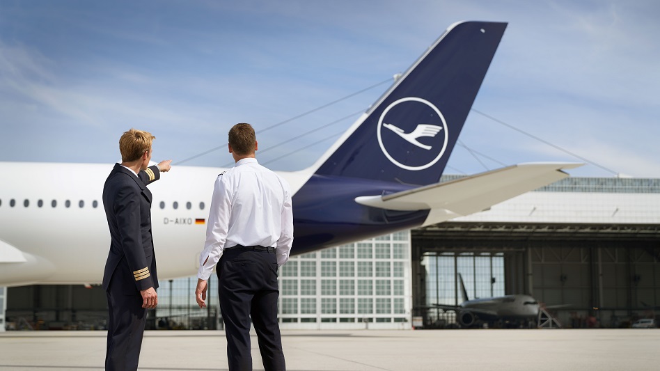 Ein First Officer steht mit einer Flugschüler:in vor einem A350 und erklärt Details.