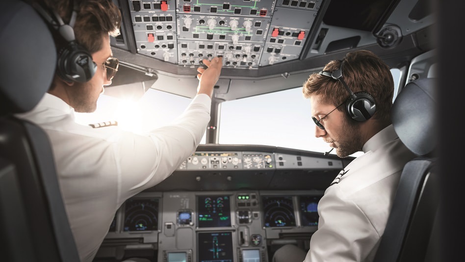 Eine Kapitän:in und ein Second Officer sitzen in einem Cockpit.