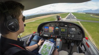 A person sits in a training aircraft and steers towards the runway.