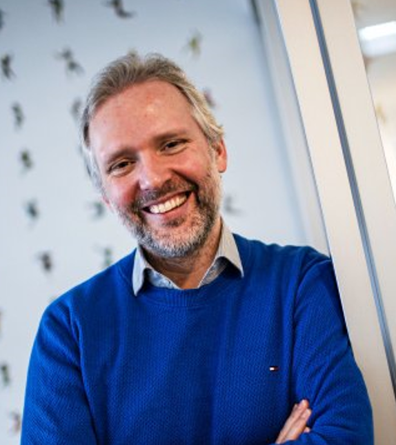 Das Bild zeigt Dr. Wannemüller mit einem blauen Pullover und Bart, der lächelnd in die Kamera blickt.